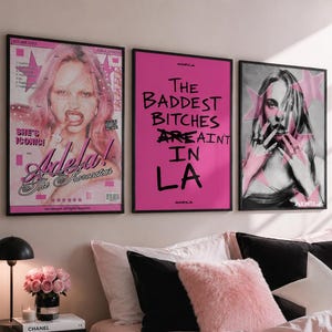 Può includere: Tre stampe da parete incorniciate che includono una copertina di rivista rosa con una persona, un poster rosa acceso con il testo nero "THE BADDEST BITCHES ARE AINT IN LA" e un ritratto in bianco e nero con grafiche di stelle rosa.