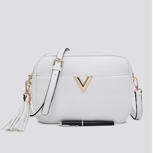 May include: A white rectangular crossbody bag with a textured surface, featuring a gold-toned V-shaped emblem on the front, a matching white tassel attached to the side, and an adjustable shoulder strap with gold-toned hardware and a black pen.