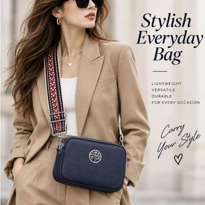 May include: A navy blue rectangular crossbody bag with a silver circular tree emblem on the front. The bag features a wide, adjustable shoulder strap with a red, white, and black geometric pattern. Text on the image reads Stylish Everyday Bag.