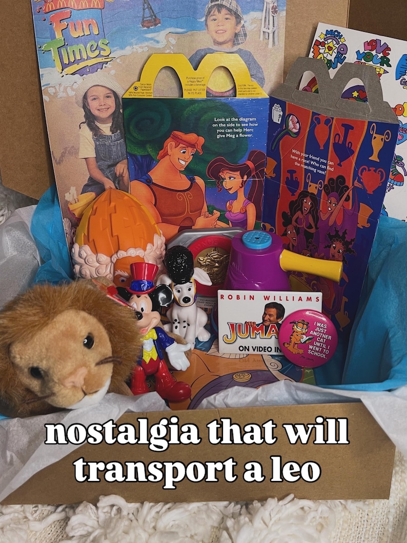May include: A collection of vintage toys and memorabilia including a McDonald's Hercules Happy Meal box, a plush lion, a Mickey Mouse figurine, a dalmatian figure, a purple plastic toy, a Jumanji video promotional card, and a Garfield pin.