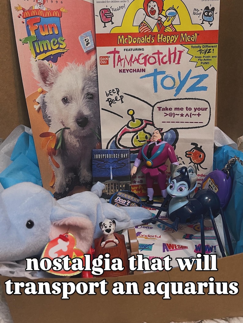 May include: A collection of 1990s McDonald's Happy Meal promotional materials and toys, including a Fun Times booklet, a Tamagotchi keychain advertisement, a small Independence Day card, a plush blue elephant, and various plastic character figures.