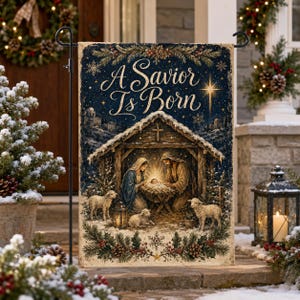 May include: A rectangular garden flag featuring a nativity scene with Mary, Joseph, and the infant Jesus in a manger under a wooden shelter. The text A Savior Is Born is printed above in gold script. The design includes sheep and pine branches.