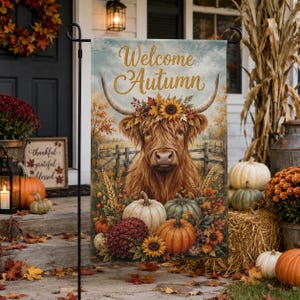 May include: A rectangular garden flag featuring a brown Highland cow with a floral crown, surrounded by pumpkins and autumn foliage. The text Welcome Autumn is printed in gold script at the top. The scene includes a wooden fence in the background.