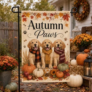 May include: A rectangular garden flag featuring the text "Autumn Paws" above three golden retriever puppies wearing knit scarves. The design includes orange, red, and yellow fall leaves, pumpkins, and paw prints on a cream-colored background.