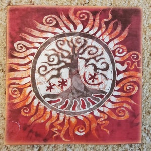 May include: Square canvas art featuring a tree of life design. The tree is centered within a white circle, surrounded by a sunburst pattern in shades of orange and red. Two red star-like shapes are near the tree's base.