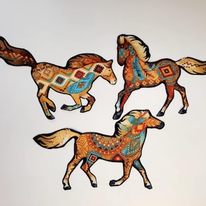 May include: Three decorative horse cutouts in a running pose. The horses feature a colorful pattern with shades of brown, orange, blue, and cream. The design incorporates geometric and tribal-inspired motifs.