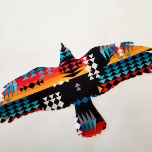 May include: A black bird silhouette with a colorful geometric pattern, featuring shades of red, orange, yellow, blue, and green. The pattern is reminiscent of Native American art.