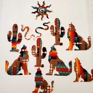May include: Southwestern-themed wall art featuring a sun, cacti, snakes, and howling wolves. The designs are in shades of brown, red, orange, and turquoise, with geometric patterns. The art is arranged on a white background.