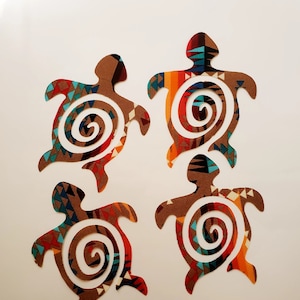 May include: Four colorful fabric turtle cutouts with a spiral design in the center. The turtles are brown, orange, red, blue, and turquoise.