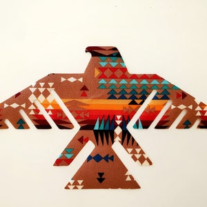 May include: A brown, red, orange, yellow, blue, and white patterned eagle silhouette. The eagle is a traditional Native American symbol.
