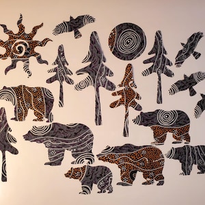 May include: A collection of cut-out shapes featuring black and orange dot-art patterns. The set includes four bears of varying sizes, five evergreen trees, a sun, a circular moon, and four birds in flight, all decorated with intricate white dots.