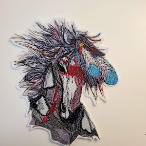 May include: Embroidered patch featuring a horse head profile with a Native American theme. The design incorporates red, blue, and black thread, with feather accents and a detailed mane. The patch is on a white background.