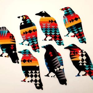 May include: Seven black crow silhouettes with geometric patterns in shades of red, orange, blue, and white. The patterns are reminiscent of Native American designs.