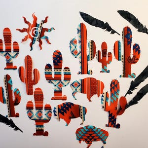 May include: A collection of fabric cutouts featuring cacti, buffalo, and a sun shape, all decorated with orange, blue, and white geometric patterns. Several black feather-shaped cutouts are arranged around the patterned fabric shapes.