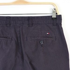 May include: Dark blue striped pants with a small red, white, and blue logo on the back pocket.