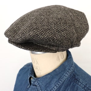 May include: A brown and black tweed newsboy cap with a slightly curved brim.