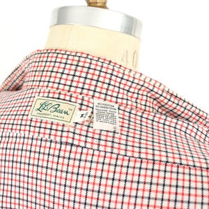 May include: A red, black, and white plaid button-down shirt with a label that reads "L.L.Bean Freeport, Maine" and includes care instructions.