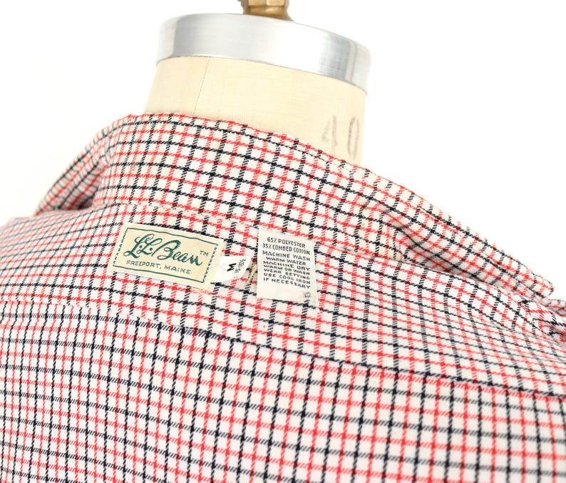 May include: A red, black, and white plaid button-down shirt with a label that reads "L.L.Bean Freeport, Maine" and includes care instructions.