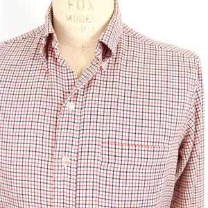 May include: A white, red, and black plaid long-sleeve button-down shirt with a single chest pocket.