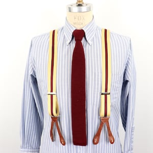 Peut inclure: Une chemise à rayures bleu clair avec une cravate bordeaux et des bretelles jaunes à rayures bordeaux. Les bretelles ont des clips en cuir.