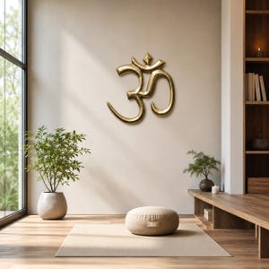 Peut inclure: Une décoration murale en forme de symbole Om doré métallique, présentant une finition lisse et polie avec des lignes courbes et un point central, fixée sur un mur uni. Le design affiche le caractère sanskrit traditionnel avec une surface réfléchissante.