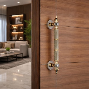 May include: A vertical door handle mounted on a wood-grain door, featuring a central cylindrical section with a light-coloured, textured pattern, accented by polished gold and silver-toned metal hardware at the top, bottom, and mounting points.