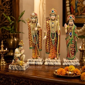 Op de afbeelding: Een set van vier versierde beeldjes met drie staande figuren in traditionele kleding met gouden, rode en groene accenten, en één knielende figuur. Elk beeldje staat op een witte, marmerachtige voet met donkergrijze aders.