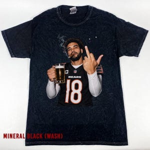 May include: A mineral black acid-wash t-shirt featuring a graphic of a person wearing a black Chicago Bears jersey with the number 18, holding a glass of beer and a cigar while gesturing with a middle finger. The shirt has a crew neck and short sleeves.