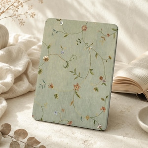 May include: A rectangular tablet or e-reader cover featuring a light sage green background with a delicate, repeating pattern of thin, winding brown vines, small green leaves, and tiny multi-colored flowers in shades of pink, blue, and yellow.