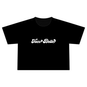 May include: A black short-sleeved t-shirt featuring the white text Taco Belle printed in a stylized, rounded cursive font across the center of the chest. The garment has a crew neckline and a straight hemline, providing a simple, clean design.