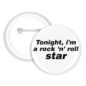 Può includere: Due spille rotonde con sfondo bianco. Una spilla presenta il testo nero Tonight, i'm a rock 'n' roll star, mentre l'altra è capovolta per mostrare il retro in metallo argentato e il meccanismo a spilla orizzontale fissato sul retro.