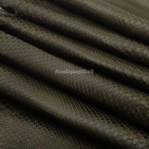 May include: A dark olive green leather material featuring a distinct, repeating scale pattern across its surface. The material is folded into several parallel layers, creating deep shadows and highlights. The text Acalapatibali is visible.