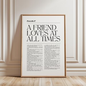 Puede incluir: Una lámina de arte mural enmarcada que presenta el texto Proverbs 17 y el título A FRIEND LOVES AT ALL TIMES en una fuente serif negra grande, seguido del texto completo del capítulo en una fuente negra más pequeña sobre fondo blanco.