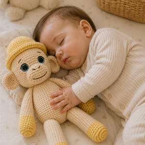 May include: A beige and yellow crocheted monkey toy featuring a small yellow hat, blue eyes, and a stitched smile. The toy includes the text CROCHET CORNER CO. at the bottom left. The monkey has light beige limbs with yellow feet and hands.
