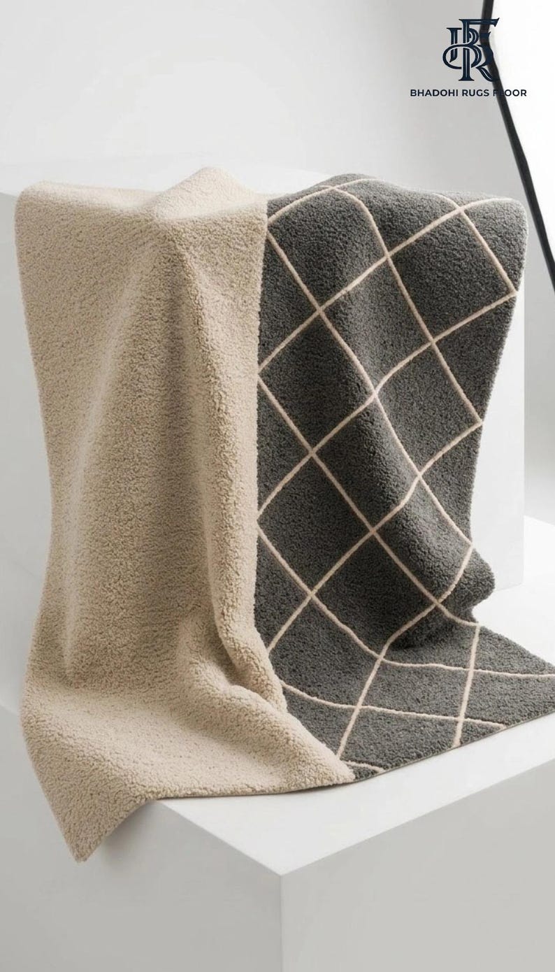 May include: A plush, textured rug featuring a two-tone design with a solid beige section and a dark gray section adorned with a white diamond grid pattern. The logo for Bhadohi Rugs Floor is visible in the upper right corner of the image.
