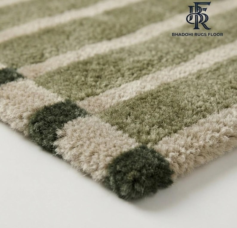 May include: A plush, high-pile area rug featuring alternating horizontal stripes in shades of sage green, olive green, and cream. The rug has a thick, textured surface and includes the logo text BHADOHI RUGS FLOOR in the upper right corner.