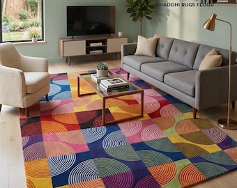 May include: A large rectangular area rug featuring a geometric pattern of multicoloured squares and concentric circles in shades of blue, yellow, pink, orange, purple, and green. The rug has a textured, carved surface design.