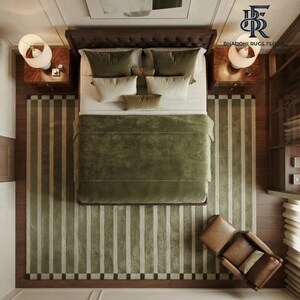 May include: A top-down view of a bedroom featuring a dark wood bed frame with a tufted headboard, covered in a solid olive green duvet and various pillows. Two wooden nightstands with white lamps flank the bed, set upon a striped olive and cream rug.
