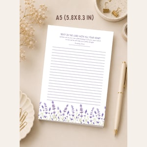 May include: A white A5 notepad measuring 14.8 by 21 cm with horizontal blue lines. The top features the text Trust in the Lord with all your heart and Proverbs 3:5-6. The bottom border displays a watercolour illustration of purple lavender.