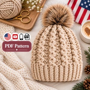 May include: A beige knit beanie featuring a textured cable stitch pattern and a large, fluffy brown faux fur pom-pom on top. A graphic overlay includes the text PDF Pattern, along with icons for the American flag, YouTube, a phone, and a PDF file.