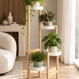 May include: A multi-tiered plant stand constructed from light-toned bamboo wood with four circular white shelves arranged at varying heights. Each shelf holds a potted plant, including a trailing vine, a patterned leaf plant, and ferns.
