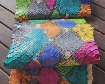 Op de afbeelding: Een veelkleurig slangenleren vel met een levendig, herhalend ruitpatroon in tinten blauw, groen, geel, oranje en roze. Het oppervlak heeft een uitgesproken, getextureerde schubbenafwerking met de tekst MatelsTanneryID zichtbaar.