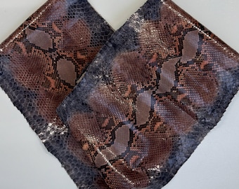 Puede incluir: Dos piezas de piel de serpiente texturizada con un patrón repetitivo de escamas marrones, bronceadas y gris oscuro. El texto MatelsTanneryID está impreso en blanco en la parte superior central de la imagen, sobre las dos secciones de piel superpuestas.
