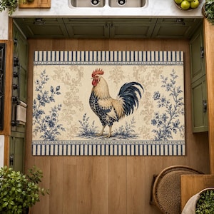 May include: A rectangular kitchen mat featuring a central rooster illustration in shades of cream, blue, and red. The design includes blue floral sprigs, a damask pattern, and striped borders at the top and bottom edges on a light beige background.