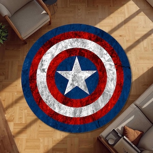 Pode incluir: Um tapete circular com um design desgastado e envelhecido de um escudo com uma estrela branca central sobre um fundo azul, rodeado por anéis alternados brancos e vermelhos. A textura da superfície parece gasta com um acabamento vintage manchado.