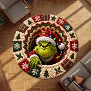 May include: A round area rug featuring a 3D-style illustration of a green character wearing a red Santa hat with colourful Christmas lights. The border has a quilted pattern with alternating squares of snowflakes, holly, and pine trees in red, green, and cream.