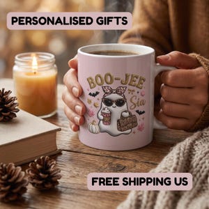 May include: A light pink ceramic mug featuring a graphic of a ghost wearing leopard print sunglasses and a matching headband, holding a coffee cup and a handbag. The text BOO-JEE Sia is printed above the ghost, surrounded by bats and leaves.