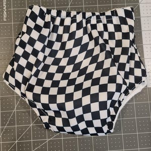May include: Black and white checkered cloth nappy with a wavy pattern. The nappy is made of a soft, absorbent material and is designed to be comfortable for babies.