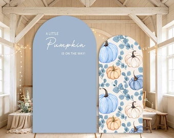 May include: Two arched backdrop covers. The left cover is solid light blue with white text reading A LITTLE Pumpkin IS ON THE WAY. The right cover features a repeating pattern of light blue, white, and orange pumpkins with blue eucalyptus leaves.