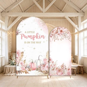 May include: Two arched backdrop covers featuring a white background with pink watercolor pumpkins, blush roses, and pampas grass. The larger arch displays the text A LITTLE PUMPKIN IS ON THE WAY in pink and gold lettering with small gold star accents.
